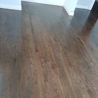 Empty room with dark wood flooring and white walls, viewed from the doorway