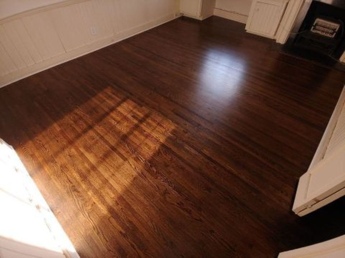 Empty room with dark wooden floor and sunlight streaming across it