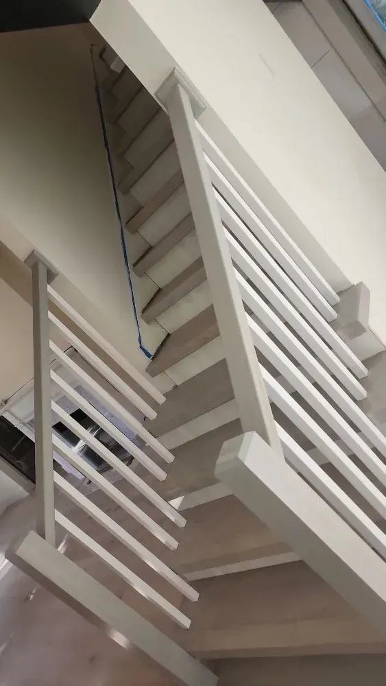 White stair railing and slatted divider in a modern interior staircase, viewed from below