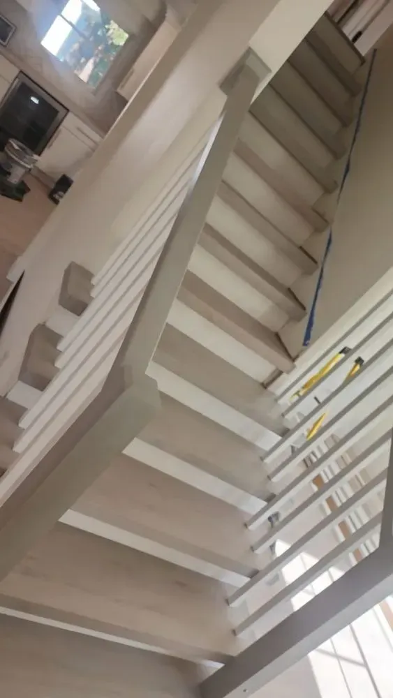 Indoor staircase with white steps and railings, viewed from below.