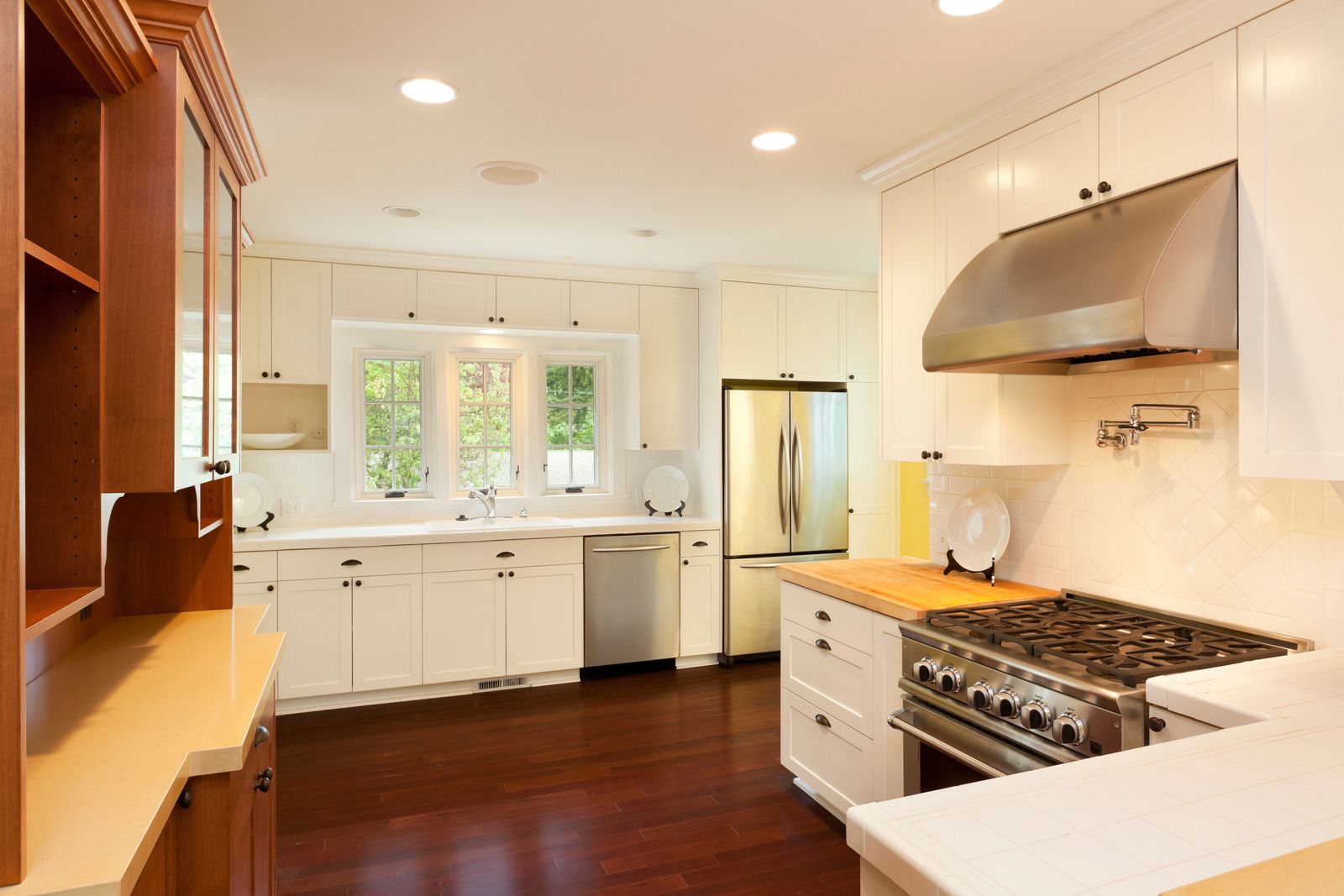 Bright white kitchen with stainless steel appliances, dark wood floors and cabinets.