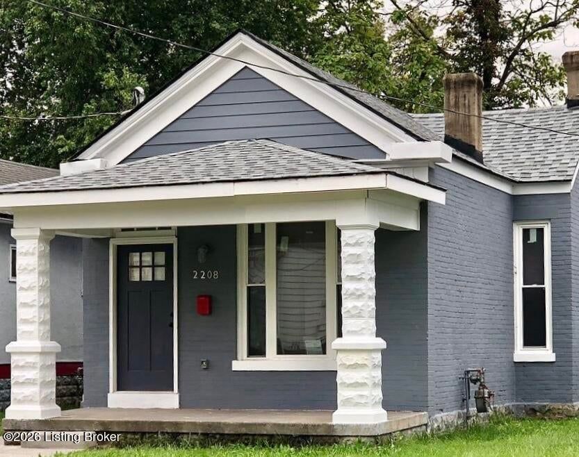Gray house with white trim and porch, dark front door, and a red mailbox plaque