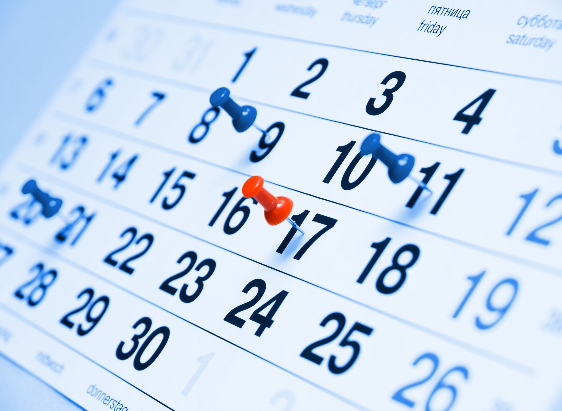 Desk calendar with blue and orange pushpins marking dates in March