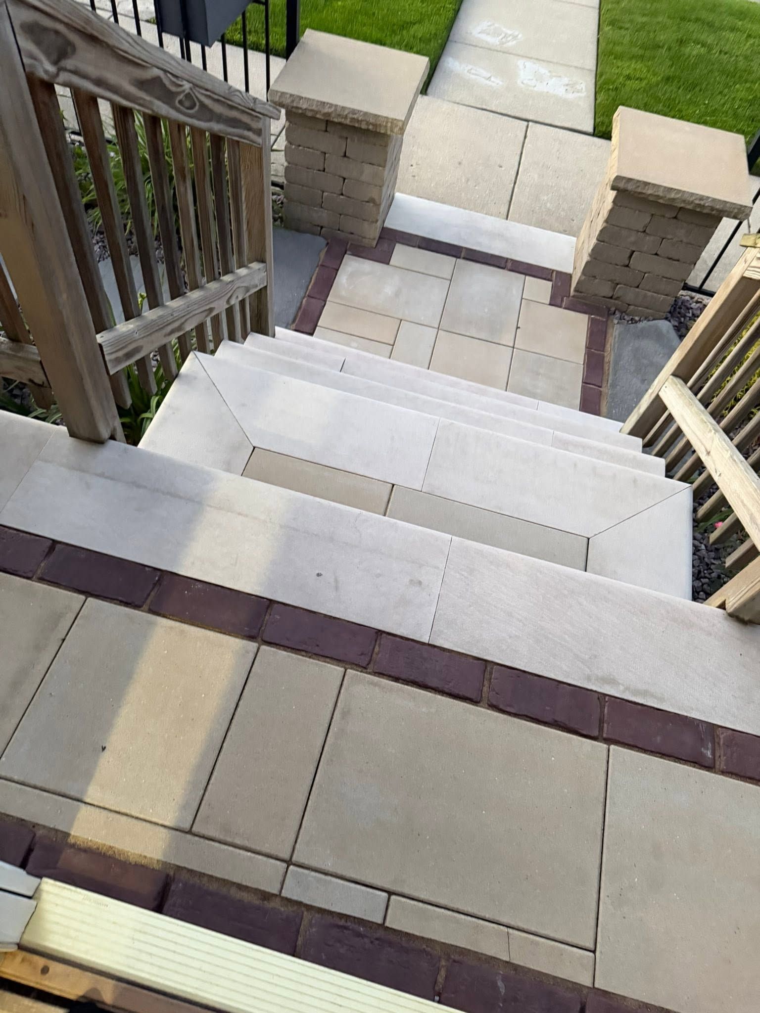 Down a white tiled front staircase with beige brick railings and sunlight casting shadows