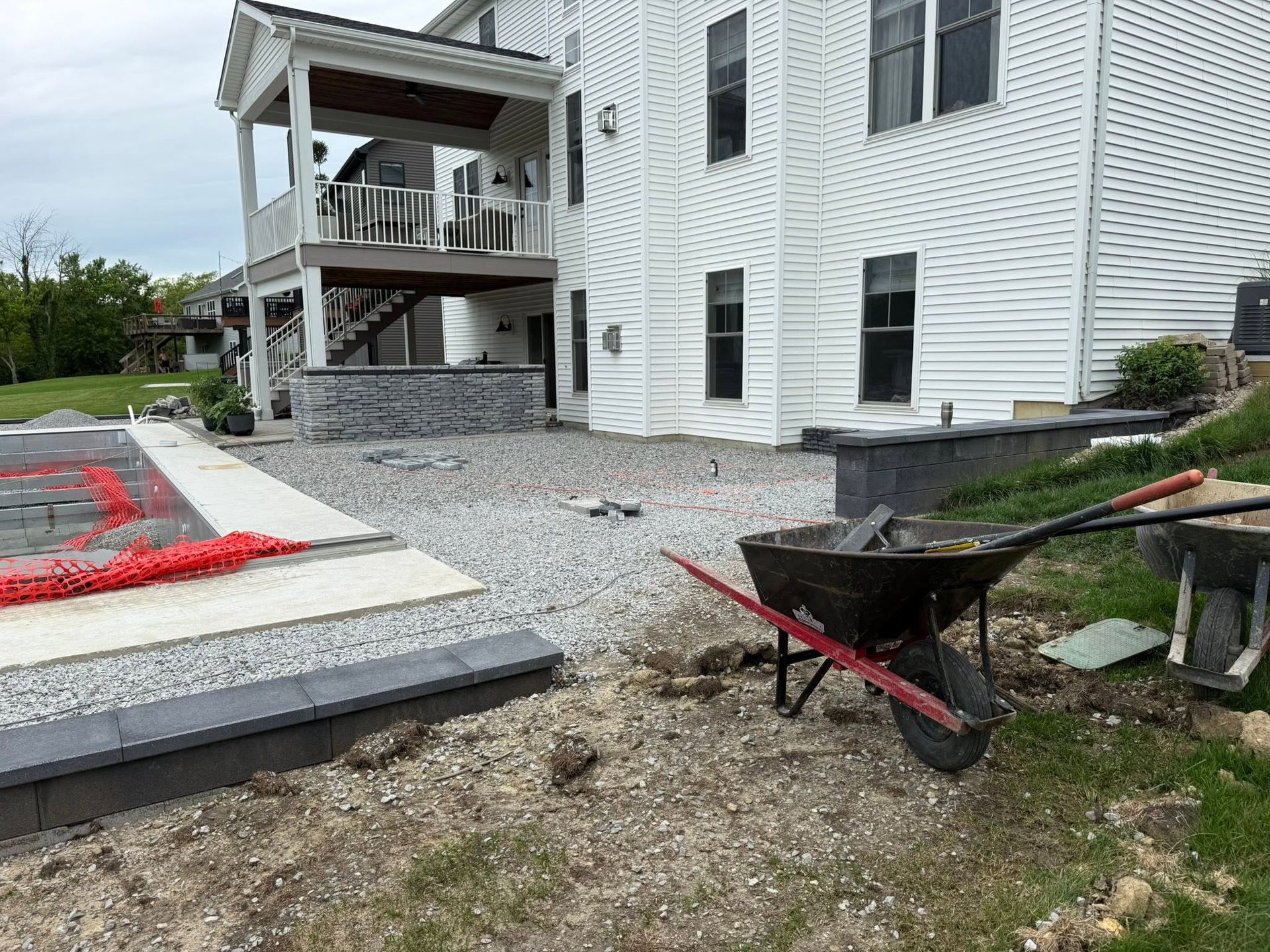 Wheelbarrow on gravel beside a white apartment building under construction