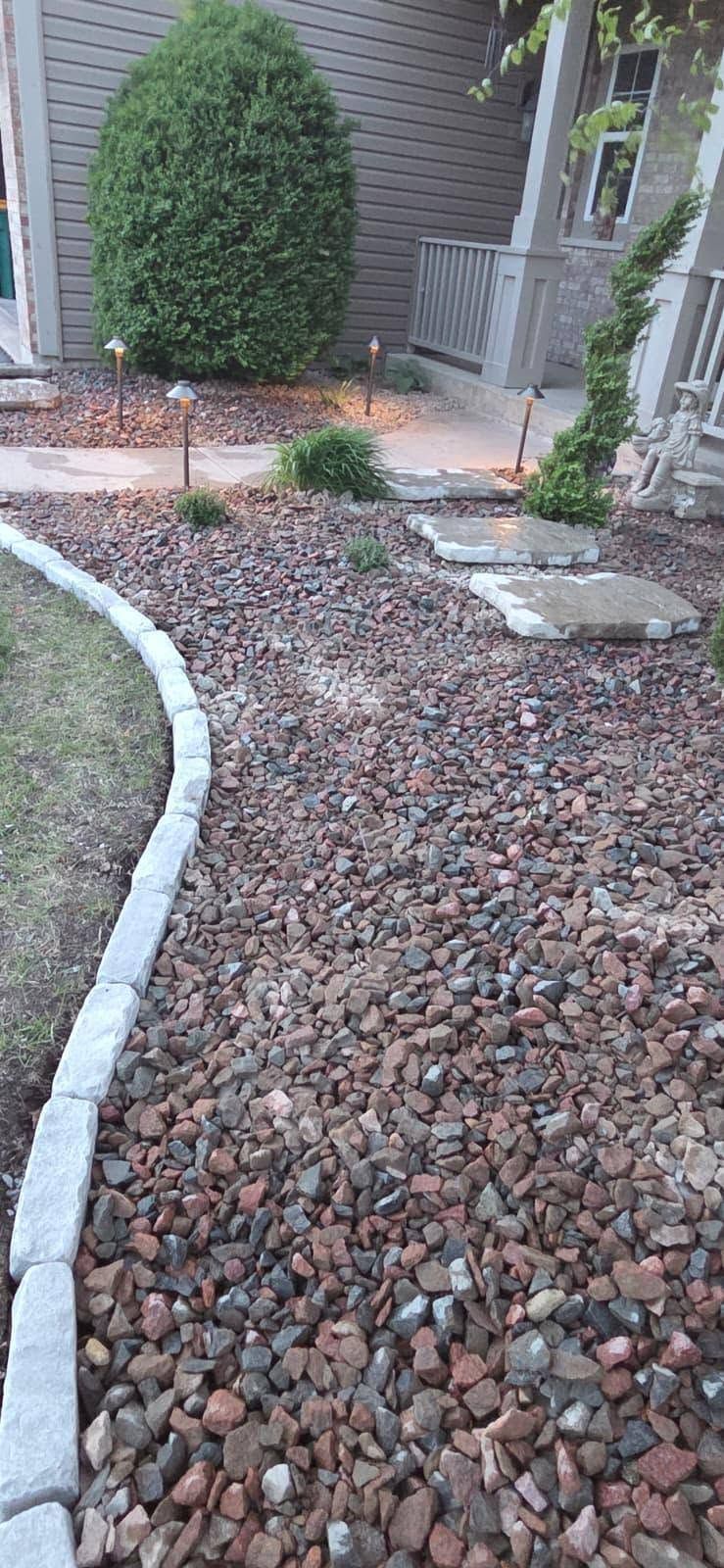 Gravel pathway beside a house, bordered by white edging and leading to a front entry with shrubs.