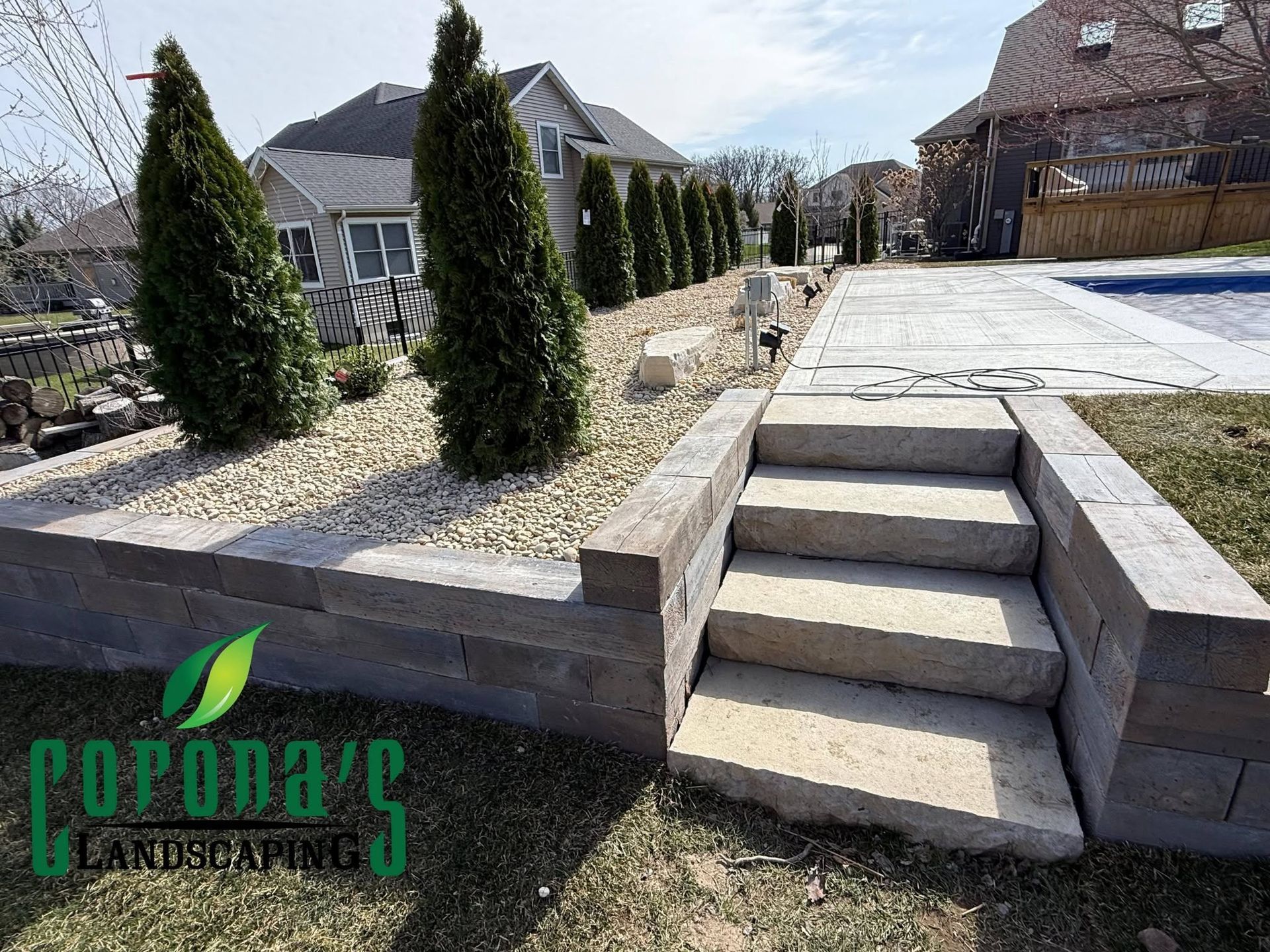 Backyard stone walkway with steps beside a landscaped gravel bed and evergreen shrubs