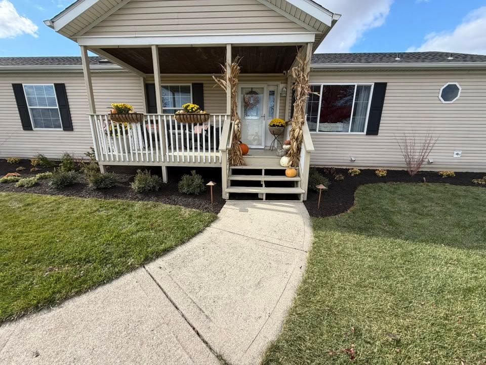 Front porch of a single-story house with beige siding, white railings, and a curved concrete walkway leading up.