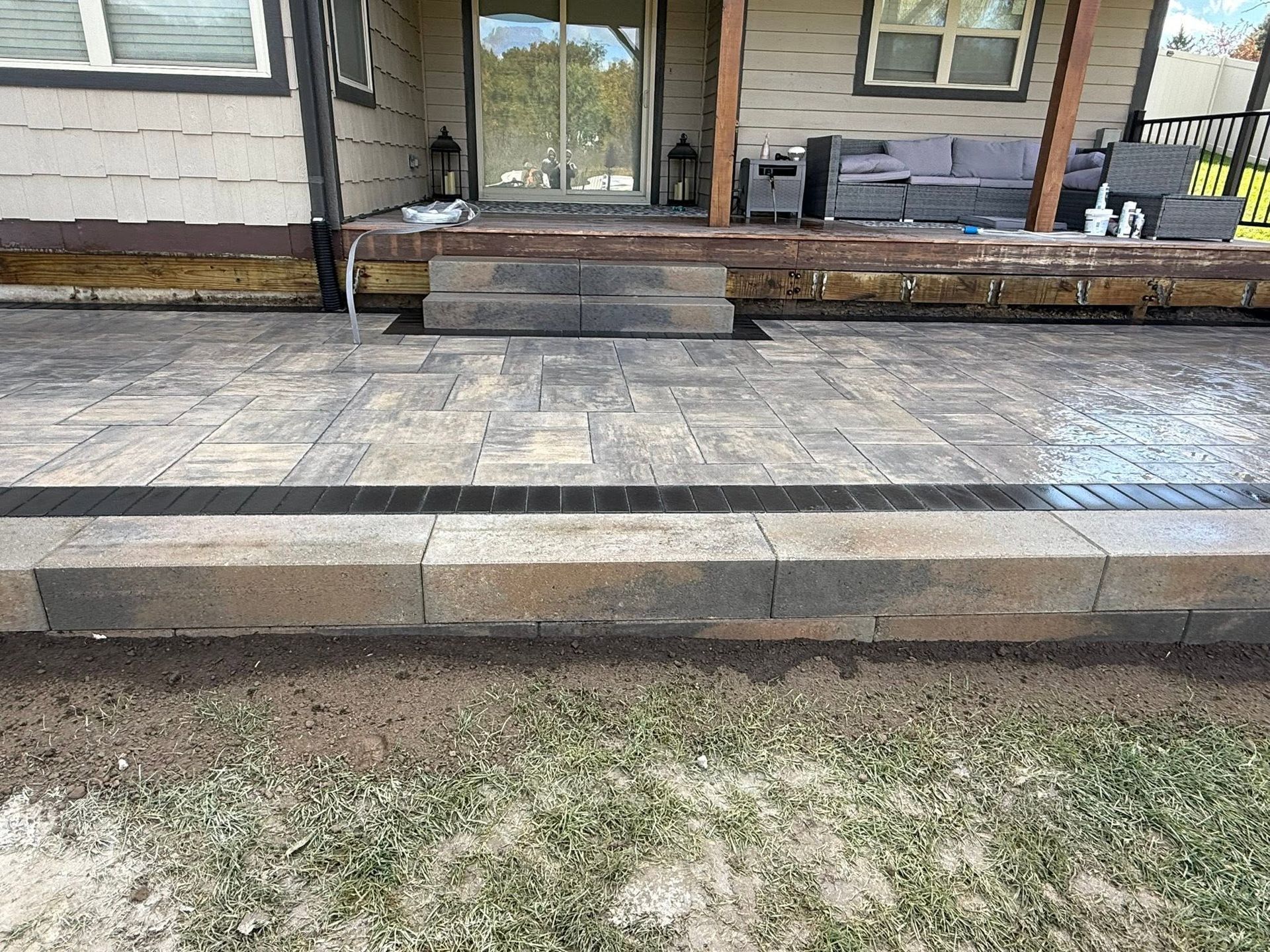 Front porch with stone patio, steps, and a glass sliding door on a house.