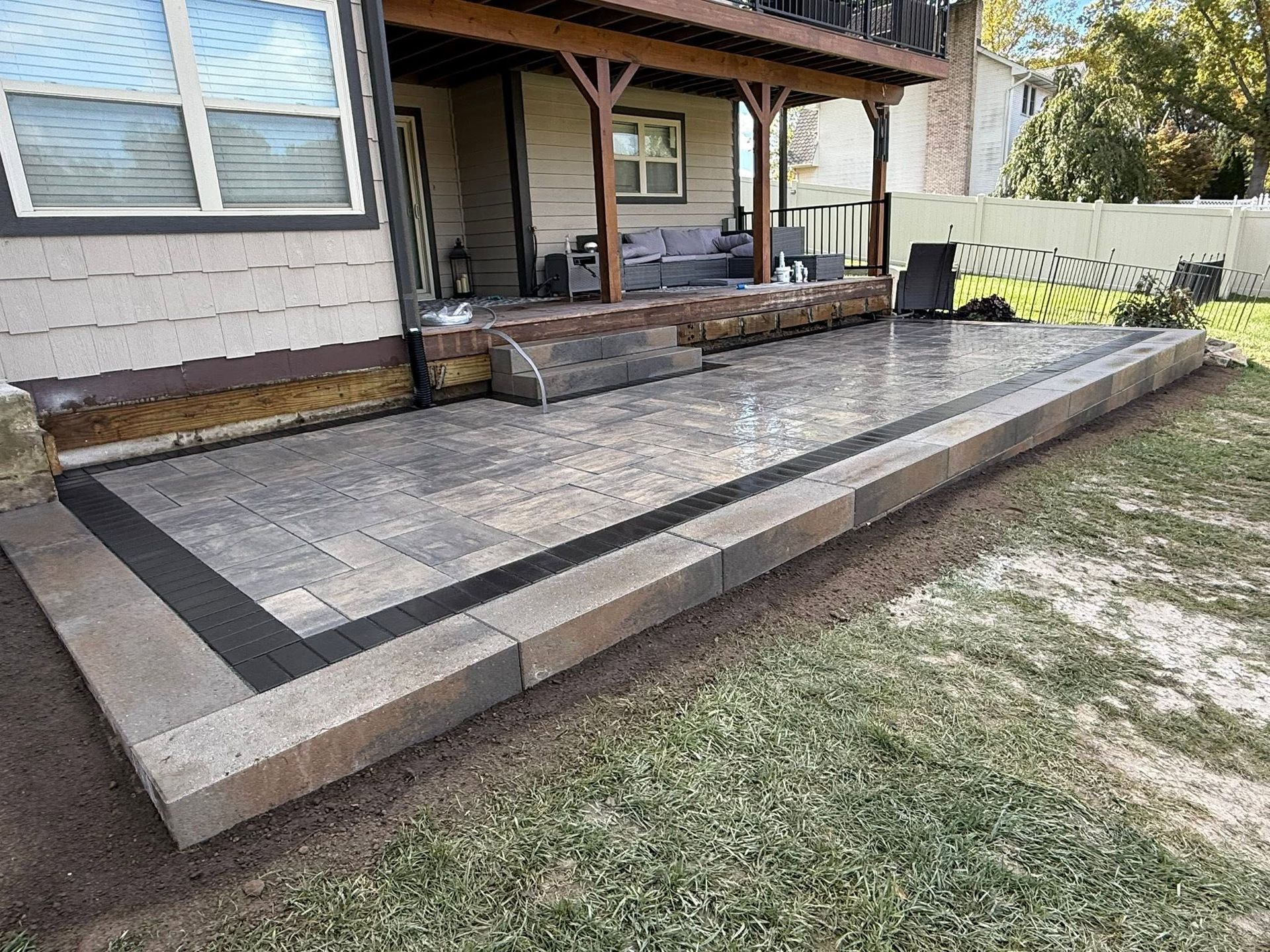 Backyard concrete patio with steps and a covered porch beside a house