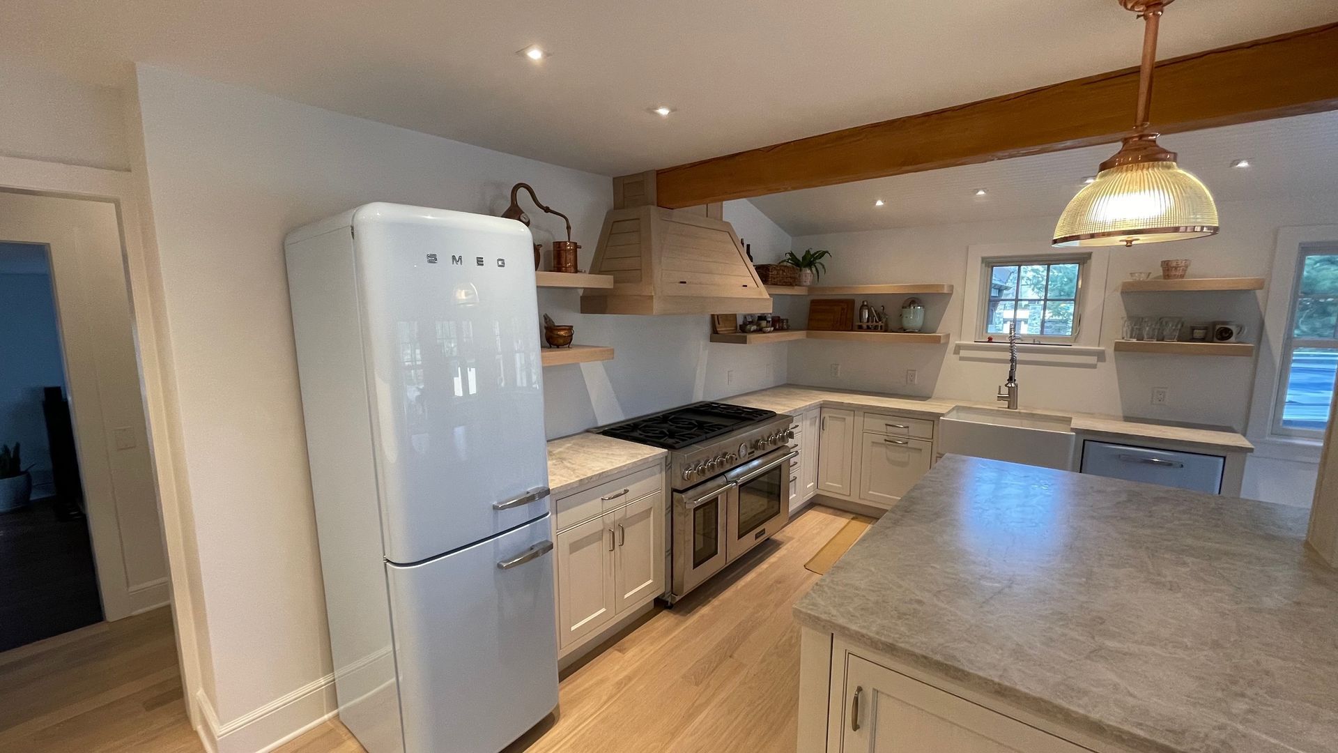 A kitchen with white cabinets , a white refrigerator , a stove , and a large island.