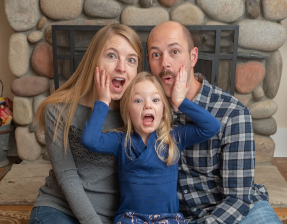 A family is posing for a picture in front of a fireplace.