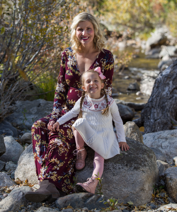 A woman and a little girl are sitting on a rock.