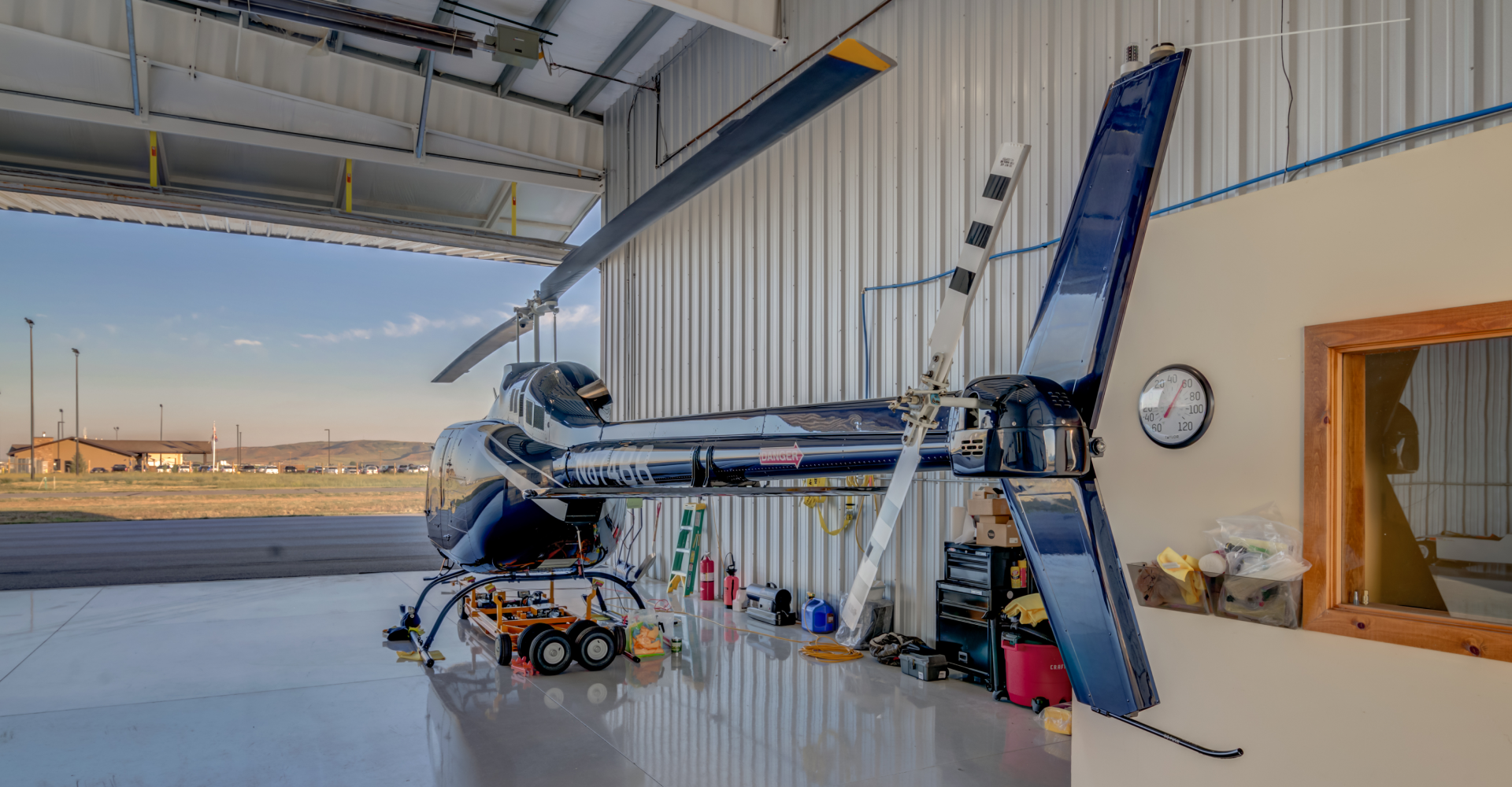 A helicopter is parked in a hangar with the door open.