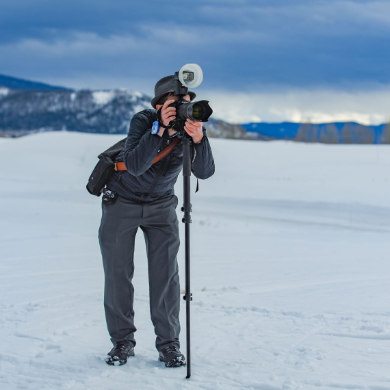 A man taking a picture with a camera in the snow