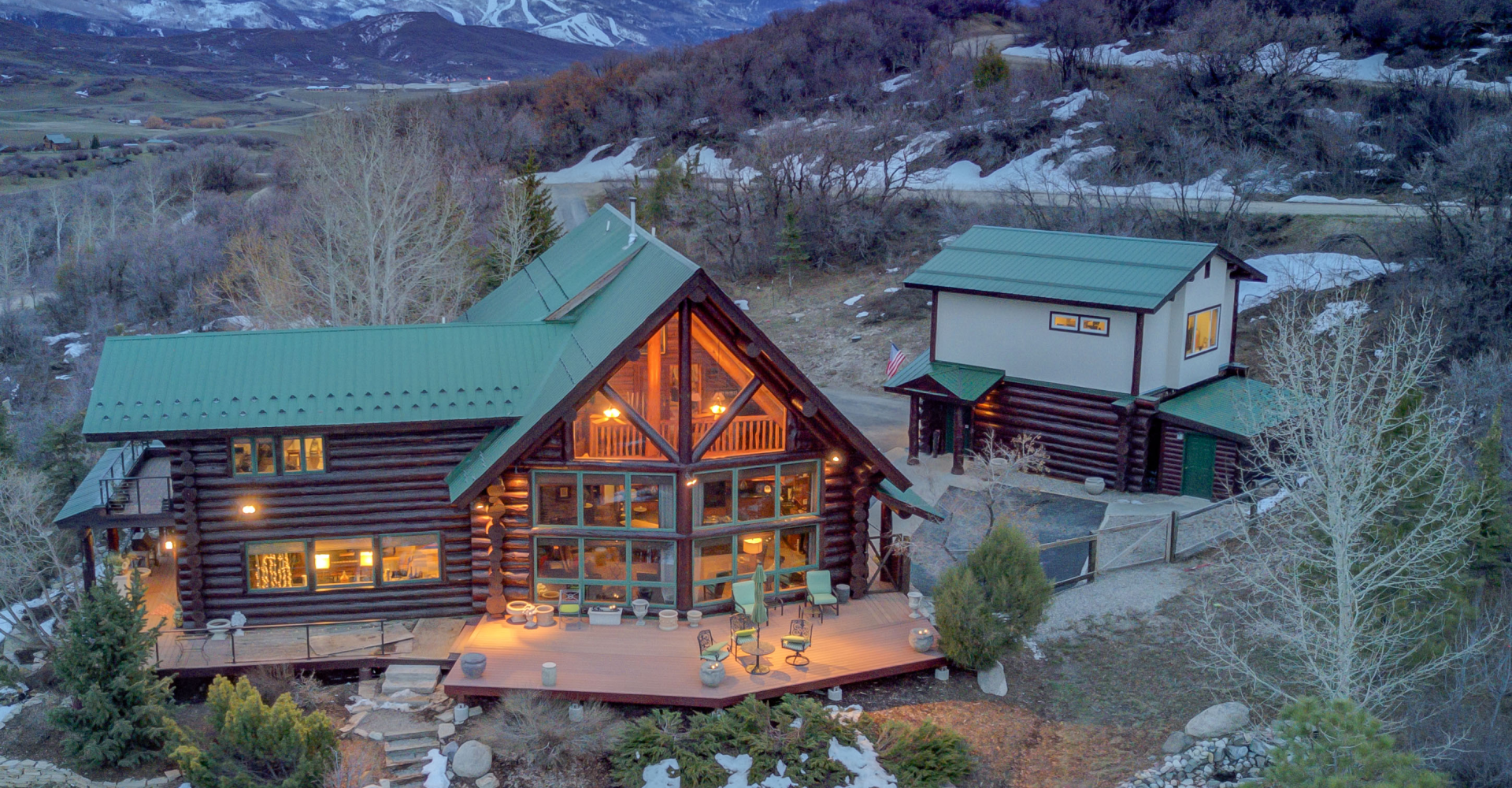 A large log cabin is sitting on top of a snow covered hill.