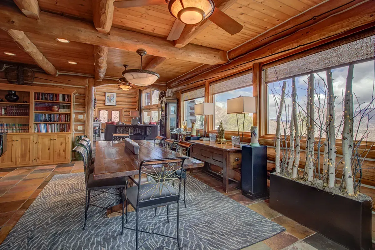 A dining room in a log cabin with a table and chairs.