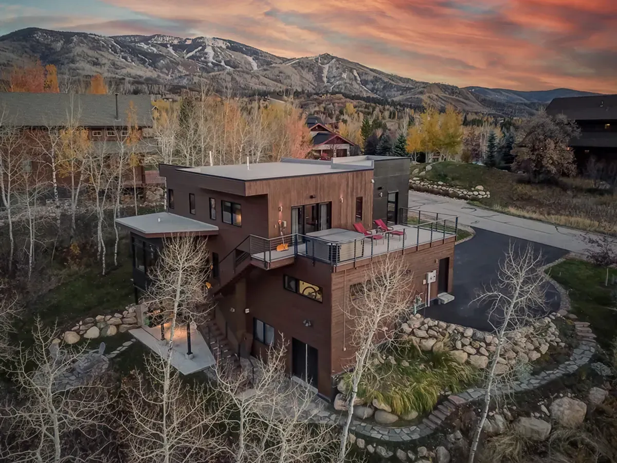 An aerial view of a large house surrounded by trees and mountains.