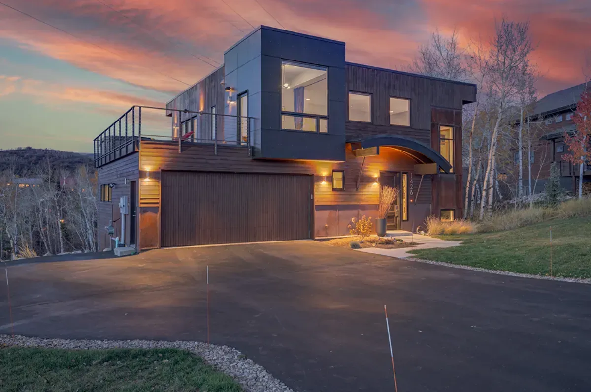 A modern house with a large garage is sitting on top of a hill.