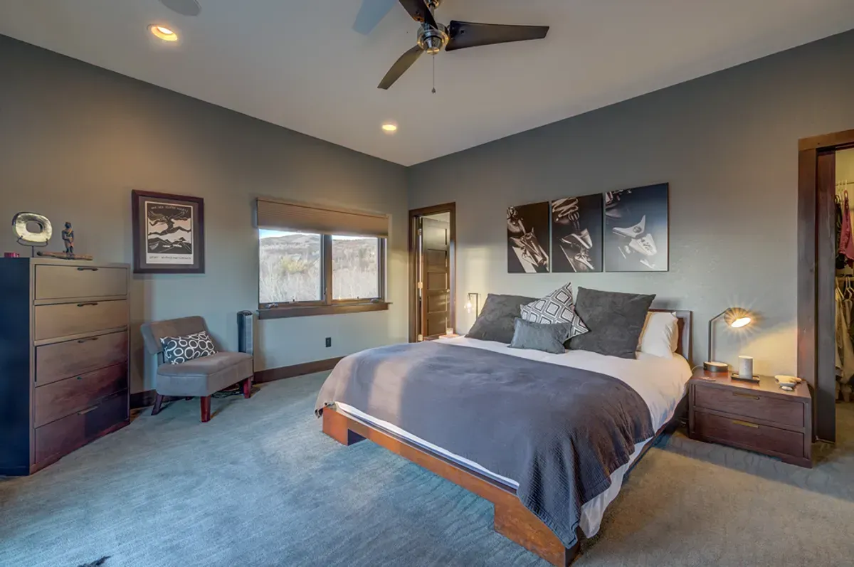A bedroom with a large bed and a ceiling fan.