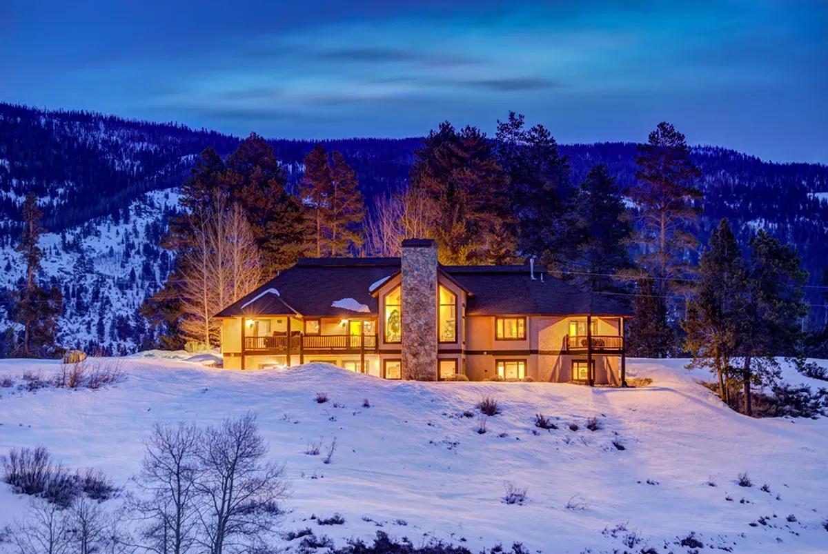 A large house is sitting in the middle of a snow covered field.