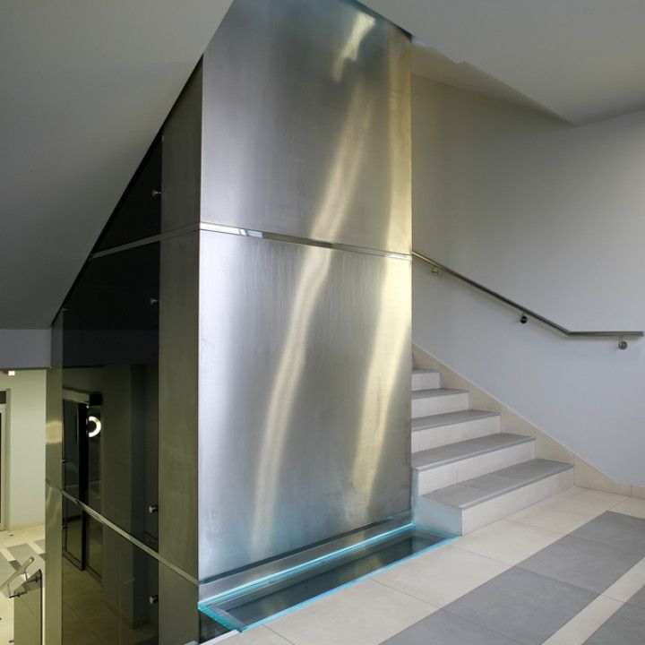 Modern indoor stairwell with stainless steel wall and glass elevator shaft
