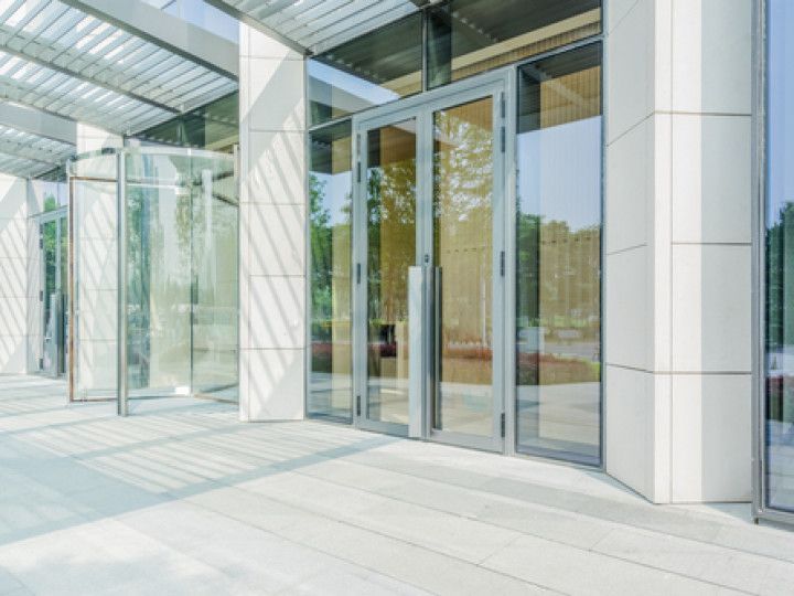 Glass entrance to a modern building with tall windows and white columns