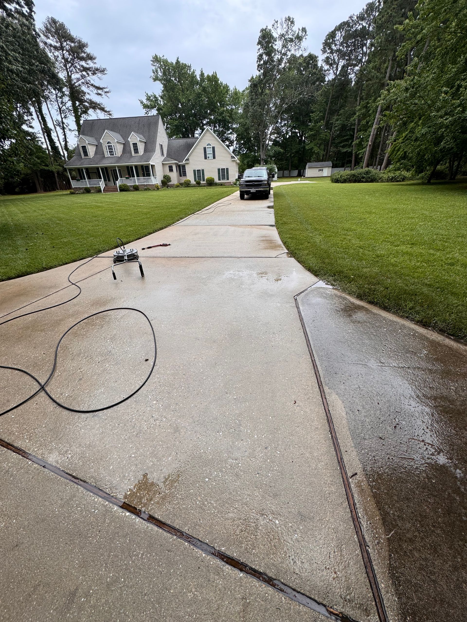 A man is using a high pressure washer to clean a brick driveway.