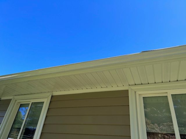 A person is cleaning a gutter with a high pressure washer.