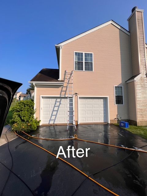 A man is cleaning the side of a house with a hose.