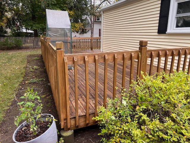 A wooden deck with a fence around it in front of a house.