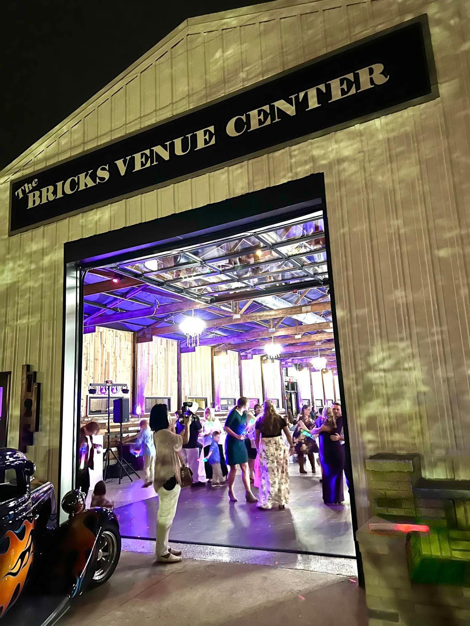 A view into The Bricks Venue Center, where a group of people gather inside a space lit with purple and warm ambient light.