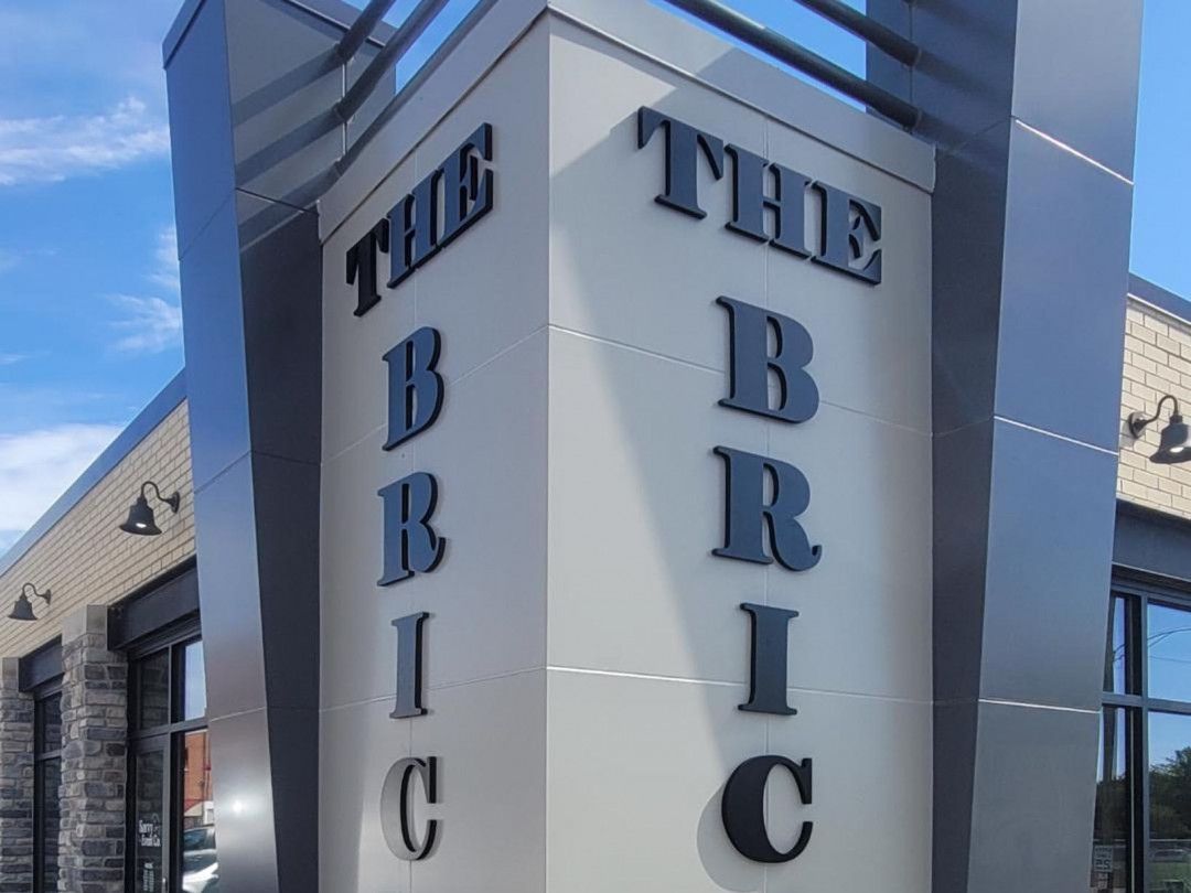 A modern, grey corner building sign featuring the words