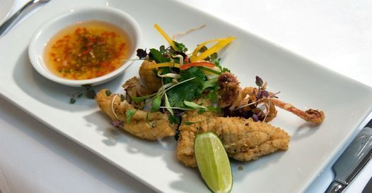Fried calamari with dipping sauce and lime wedge on white plate.