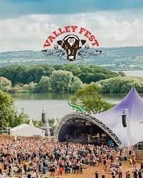 Valley Fest music festival with a crowd, stage, lake, and logo.