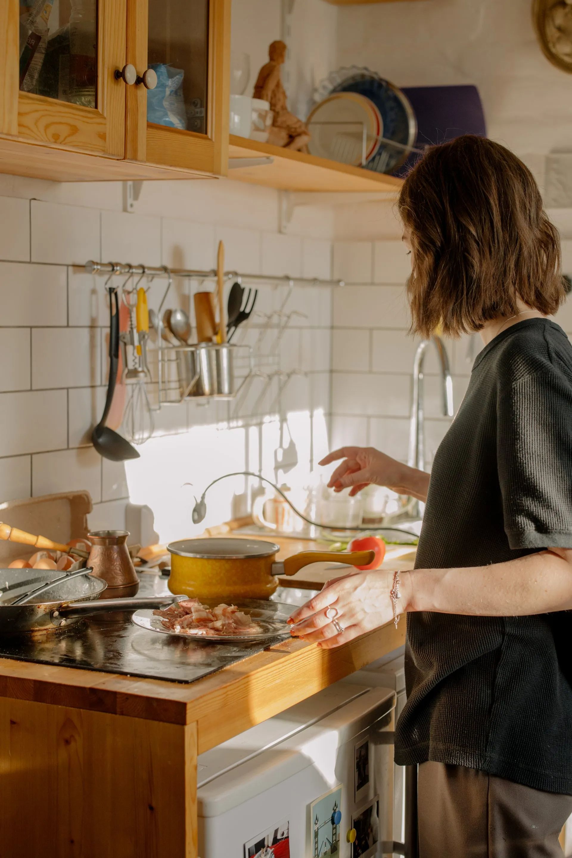 Woman cooking at a stove in a bright kitchen.