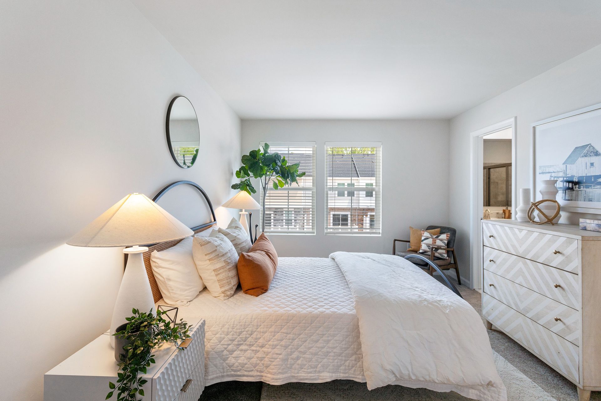 A bedroom with a king size bed , dresser , nightstand and two lamps.