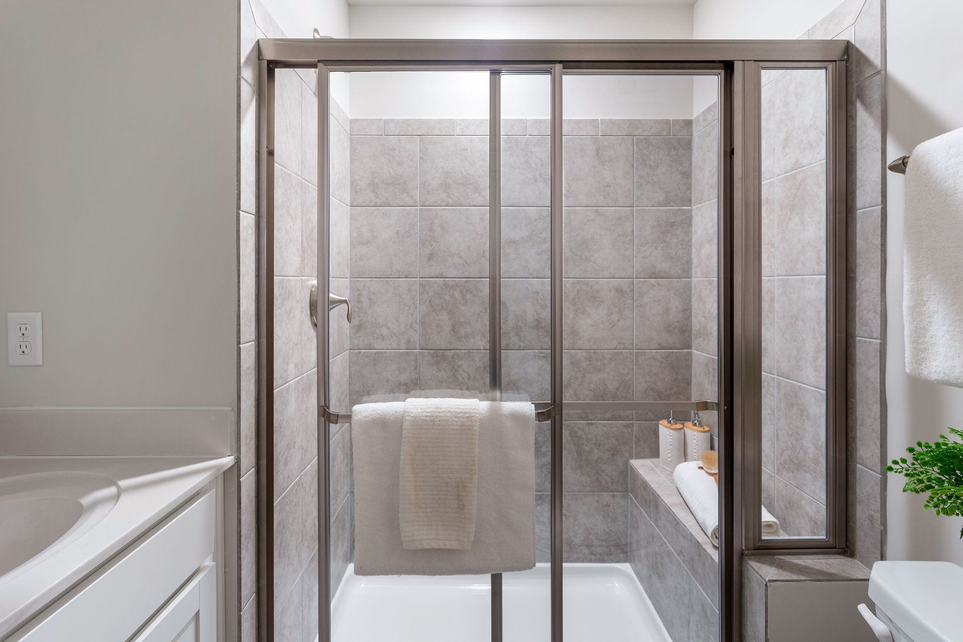 A bathroom with a sliding glass shower door and a bathtub.