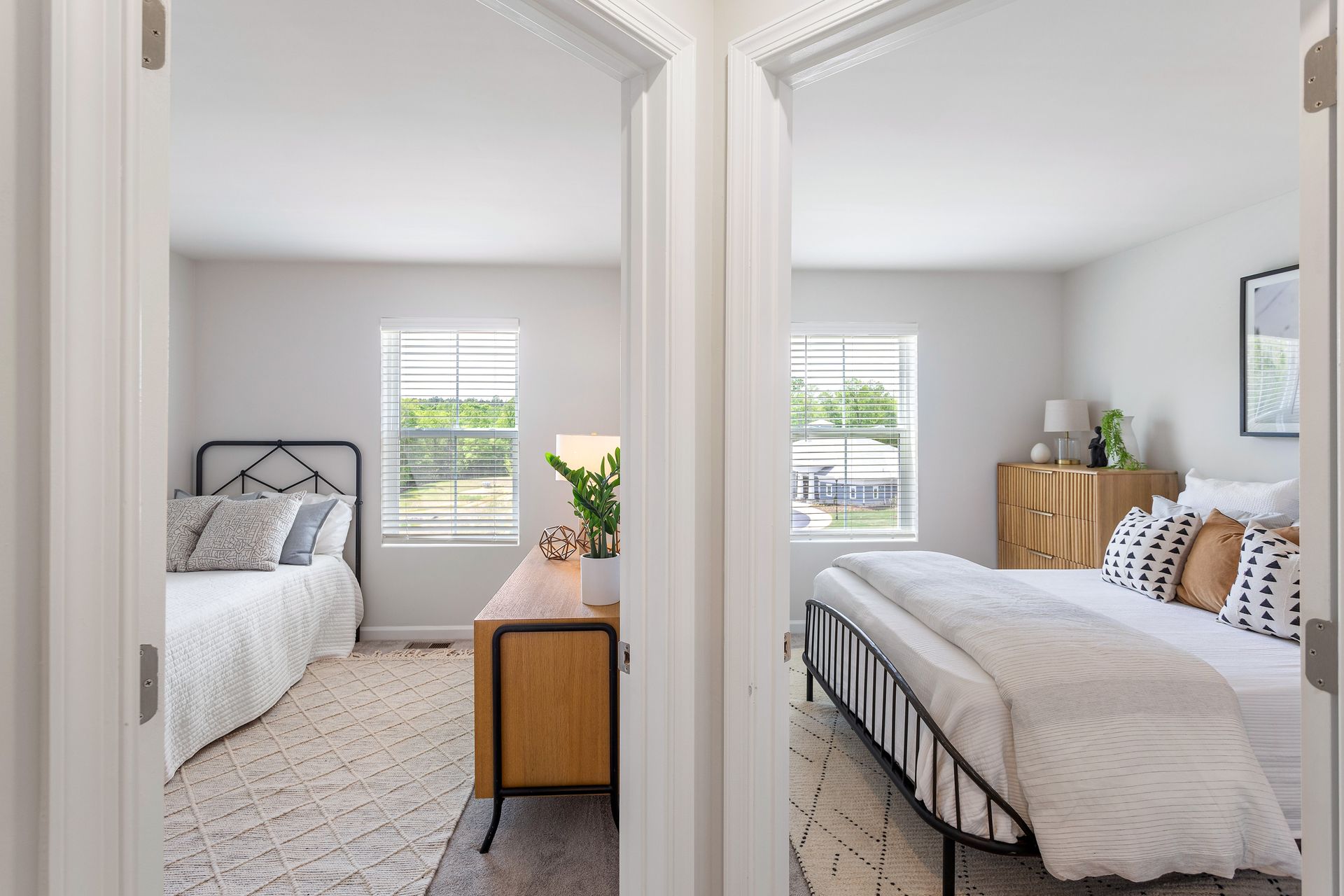 A bedroom with two beds , a dresser , and two windows.