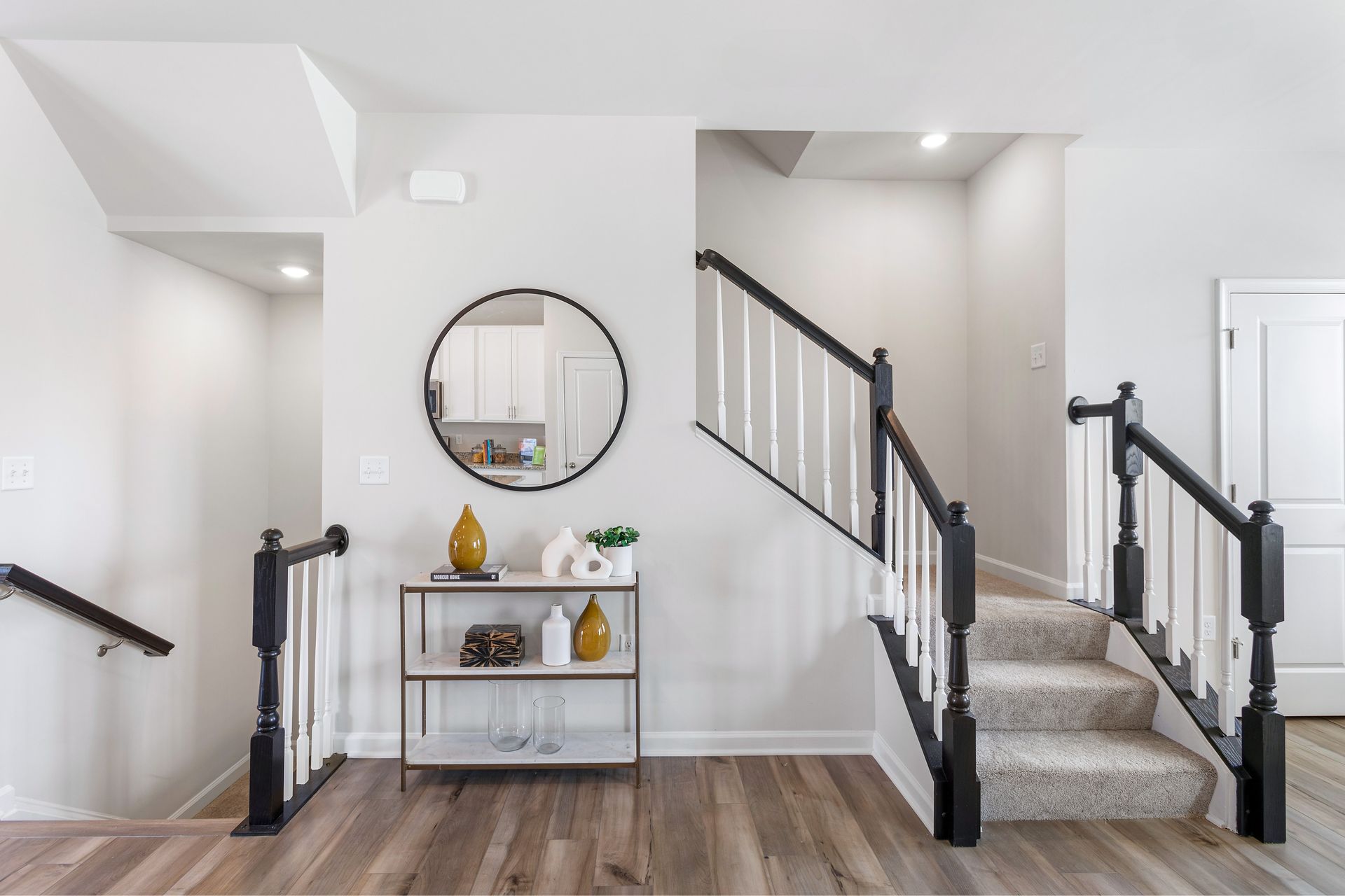 A hallway with stairs and a mirror on the wall.