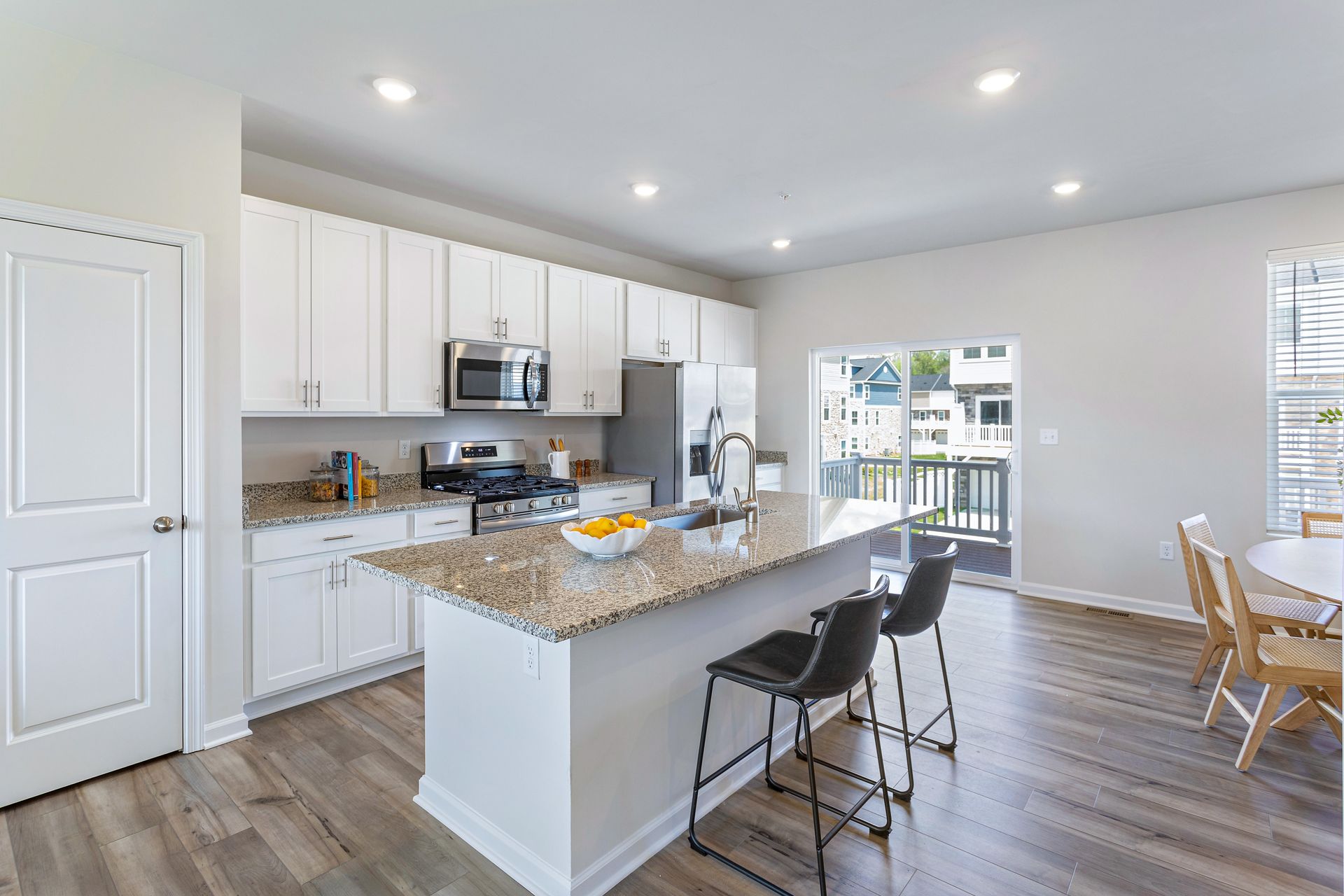 A kitchen with white cabinets , granite counter tops , stainless steel appliances and a large island.