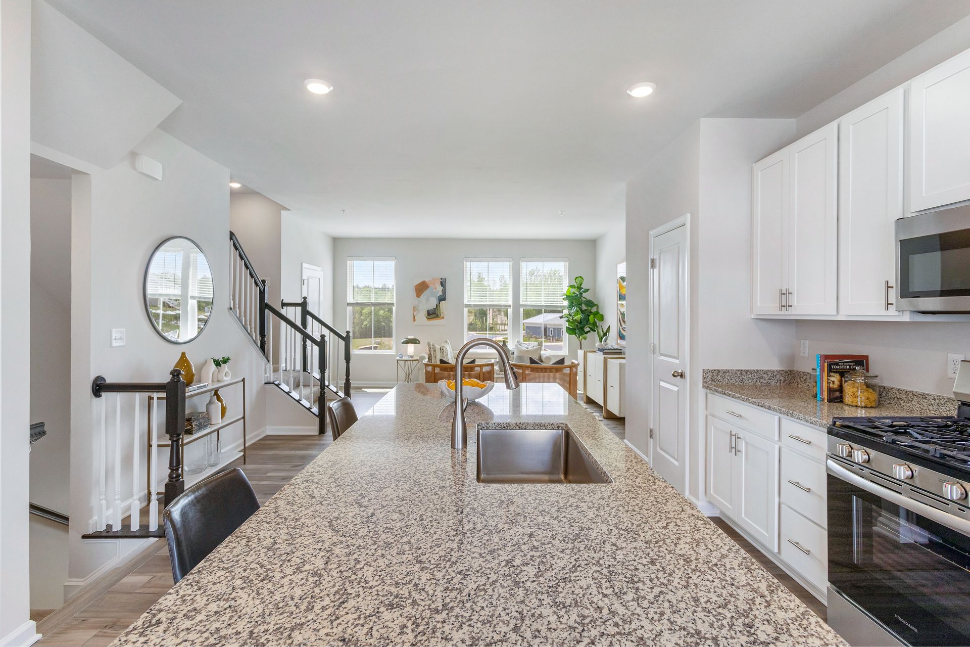 A kitchen with granite counter tops , stainless steel appliances , and white cabinets.