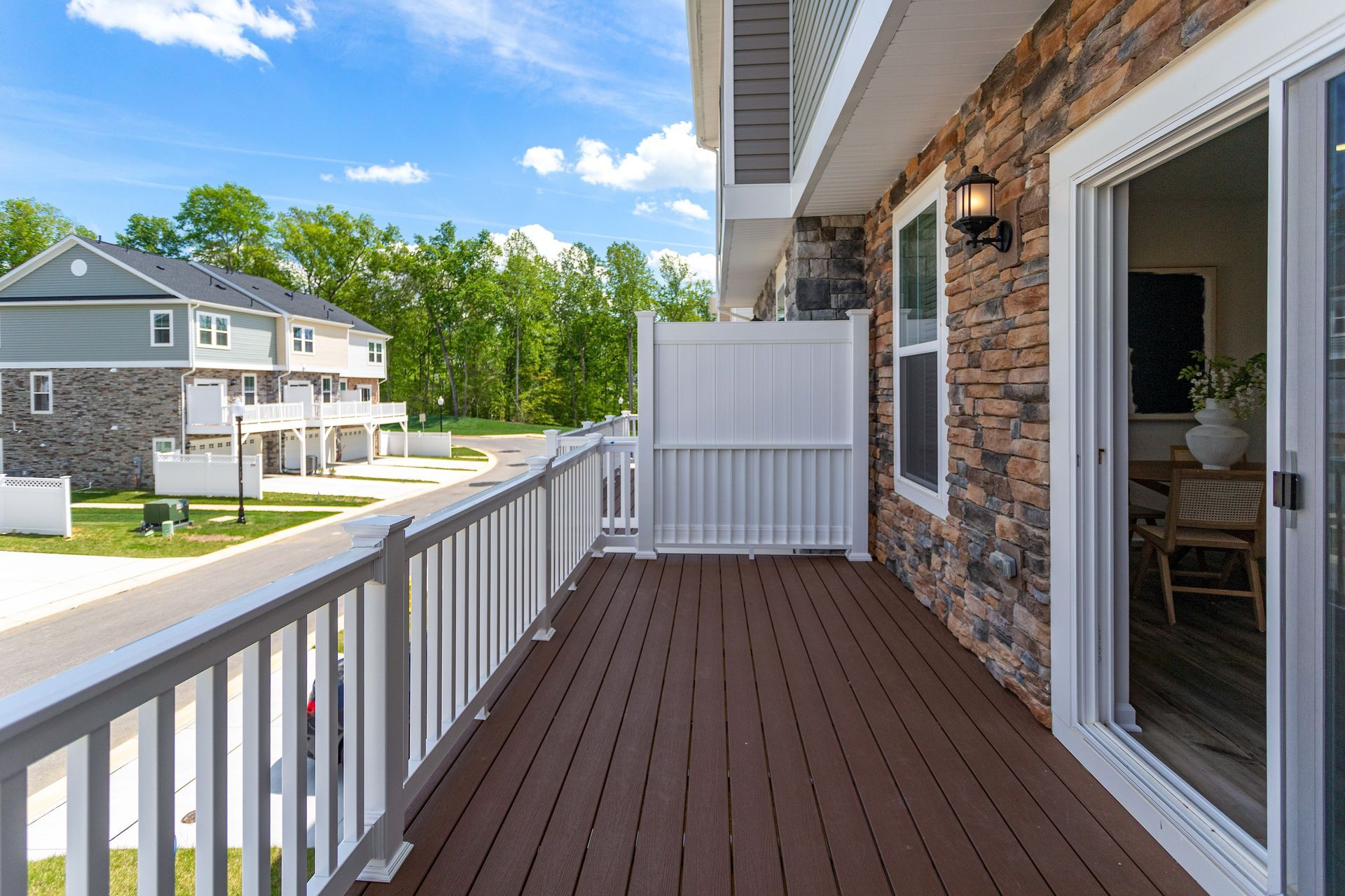 A large deck with a white railing and sliding glass doors.