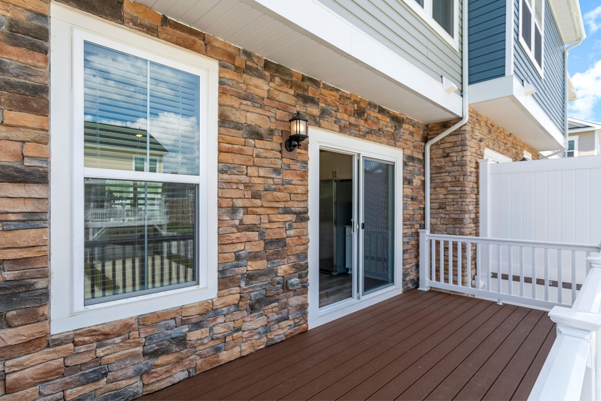 A brick house with a wooden deck and sliding glass doors.