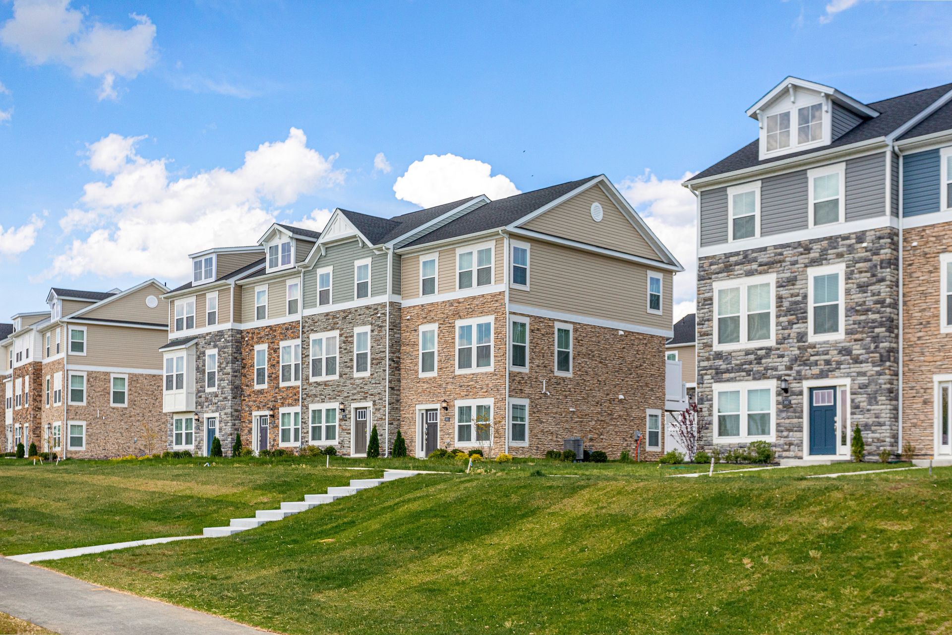 A row of apartment buildings sitting next to each other on a lush green hillside.