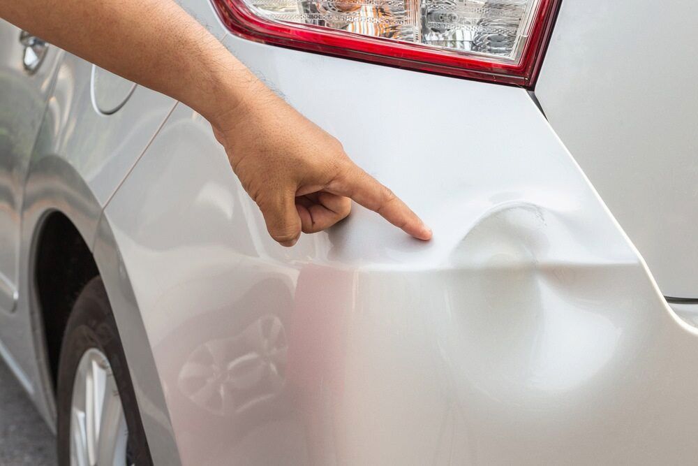 A Person is Pointing at a Damaged Car Bumper — Seabreeze Auto Body in Coffs Harbour, NSW