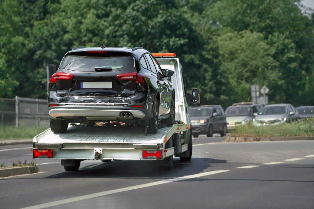 A Car is Being Towed by a Tow Truck on a Highway — Seabreeze Auto Body in Coffs Harbour, NSW
