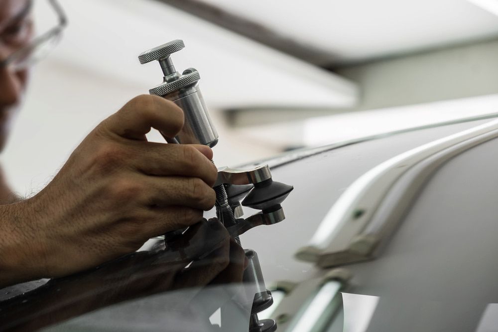 A Man is Repairing a Windshield on a Car — Seabreeze Auto Body in Coffs Harbour, NSW