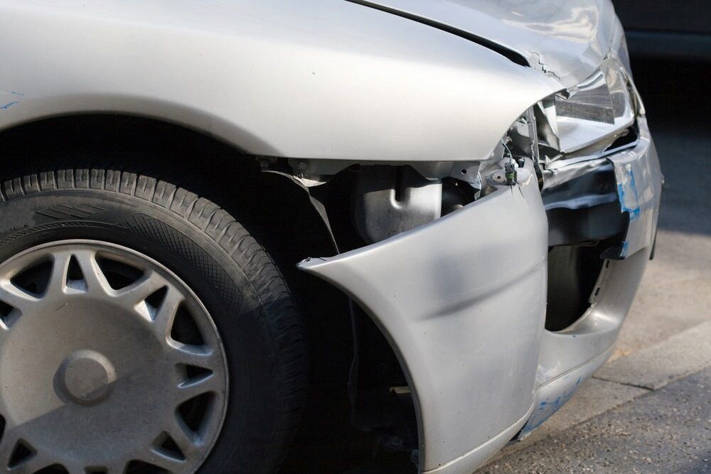 A Silver Car With a Damaged Bumper is Parked on the Side of the Road — Seabreeze Auto Body in Coffs Harbour, NSW