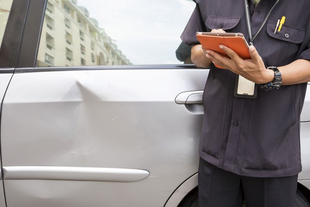 A Man is Standing Next to a Car Holding a Clipboard — Seabreeze Auto Body in Coffs Harbour, NSW